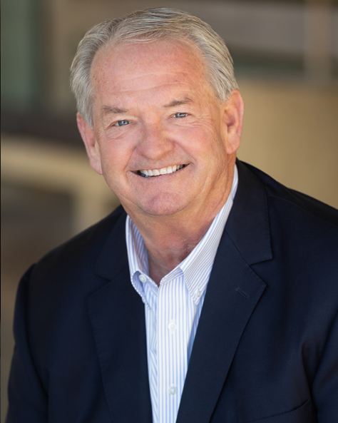 Portrait of Richard Meginnis, SIOR, President of NAI FMA Realty, smiling in a professional setting.