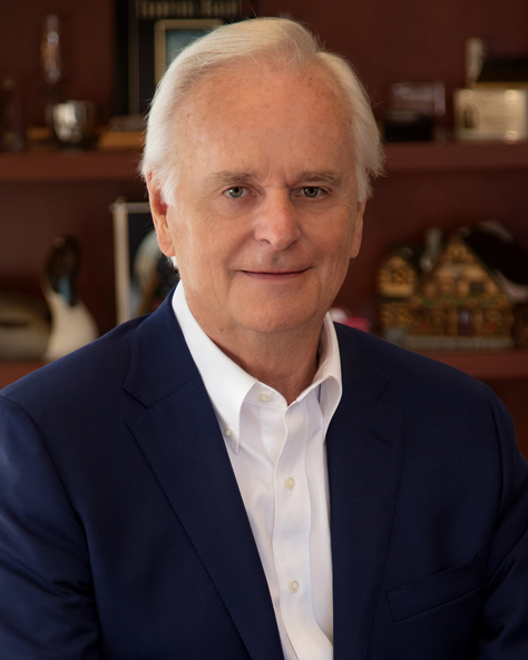 Portrait of Tom Ball, Principal Owner at NAI FMA Realty, seated at a desk in an office.